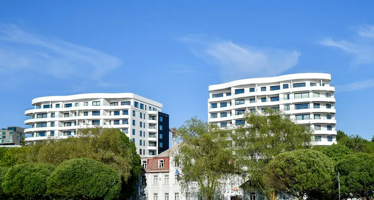 Helle Wohnhäuser im Grünen unter blauem Himmel